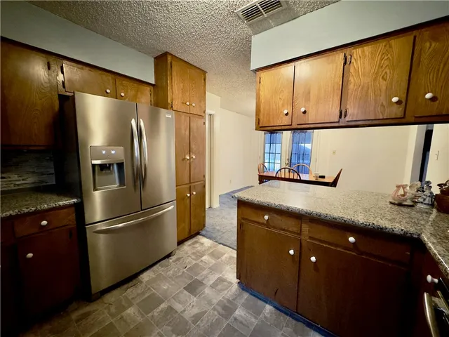 a kitchen with stainless steel appliances granite countertop a refrigerator a sink and cabinets