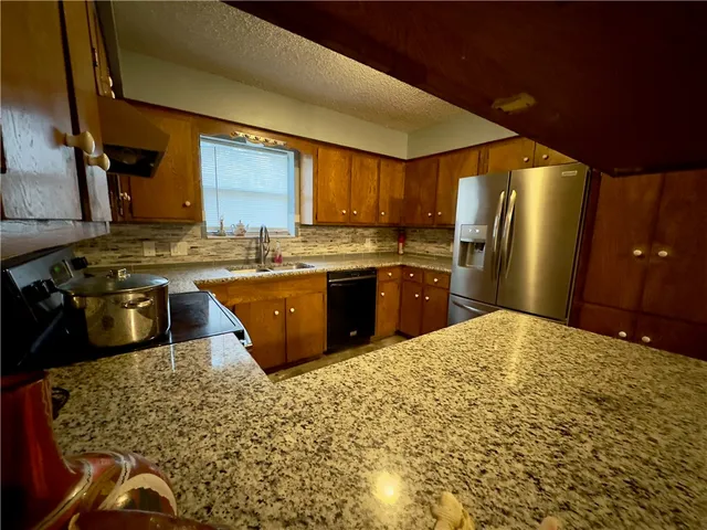 a kitchen with stainless steel appliances granite countertop a sink stove and refrigerator