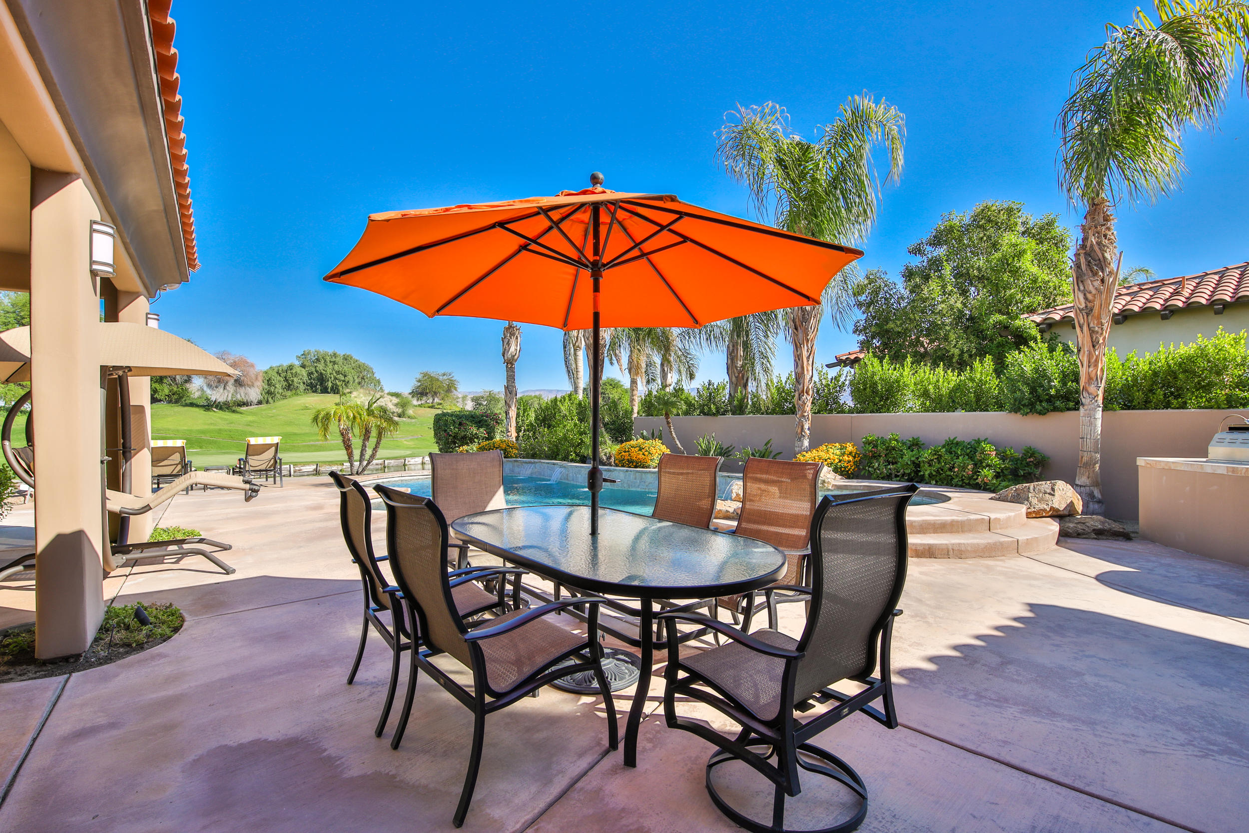 360 Loch Lomond Road Rancho Mirage, CA 92270 - Photo 30 of 76 a view of a backyard with table and chairs under an umbrella