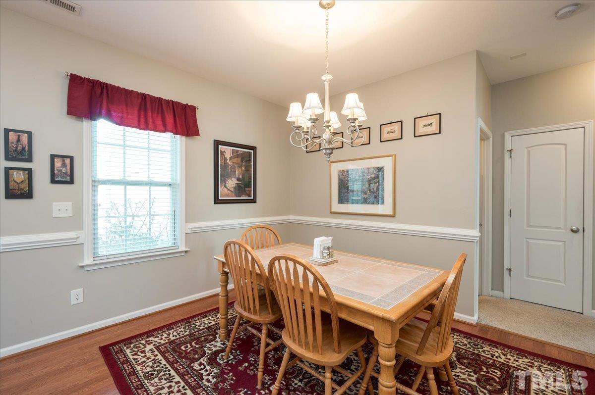 3900 Joe And Ruth Lee Drive Raleigh, NC 27610 - Photo 3 of 25 a dining room with wooden floor a chandelier a wooden table and chairs