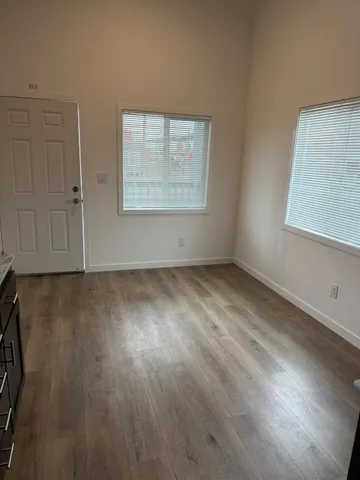 an empty room with wooden floor and windows