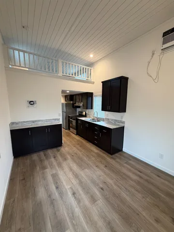 a living room with hard wood floors and a kitchen space