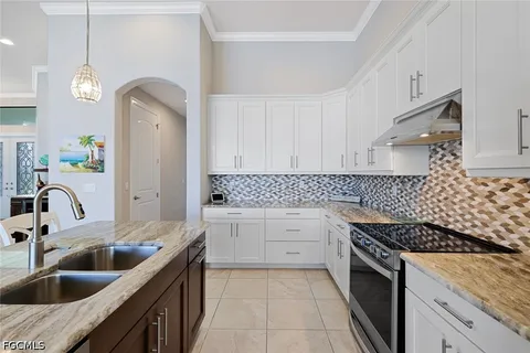 a kitchen with granite countertop a sink a stove and cabinets