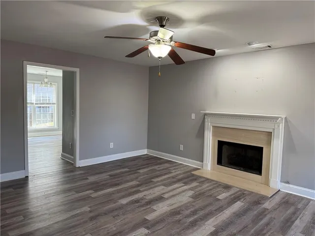 a view of an empty room with wooden floor fireplace and a window