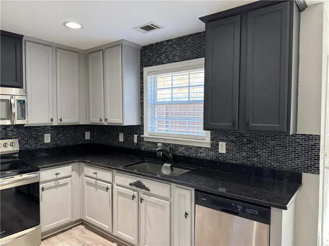 a kitchen with granite countertop a sink and a white cabinets