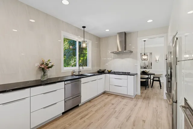 a kitchen with white cabinets a sink a window and stainless steel appliances