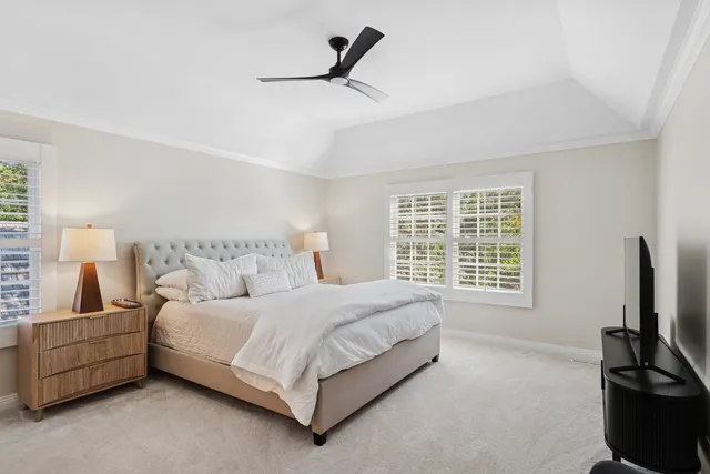 a bedroom with a bed a couch and a flat tv screen on the dresser