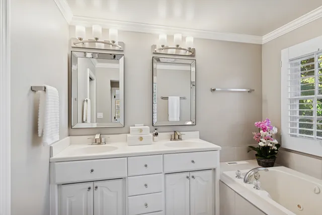 a bathroom with double vanity sinks a mirror and a bathtub