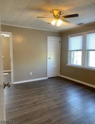 a view of an empty room with window and wooden floor