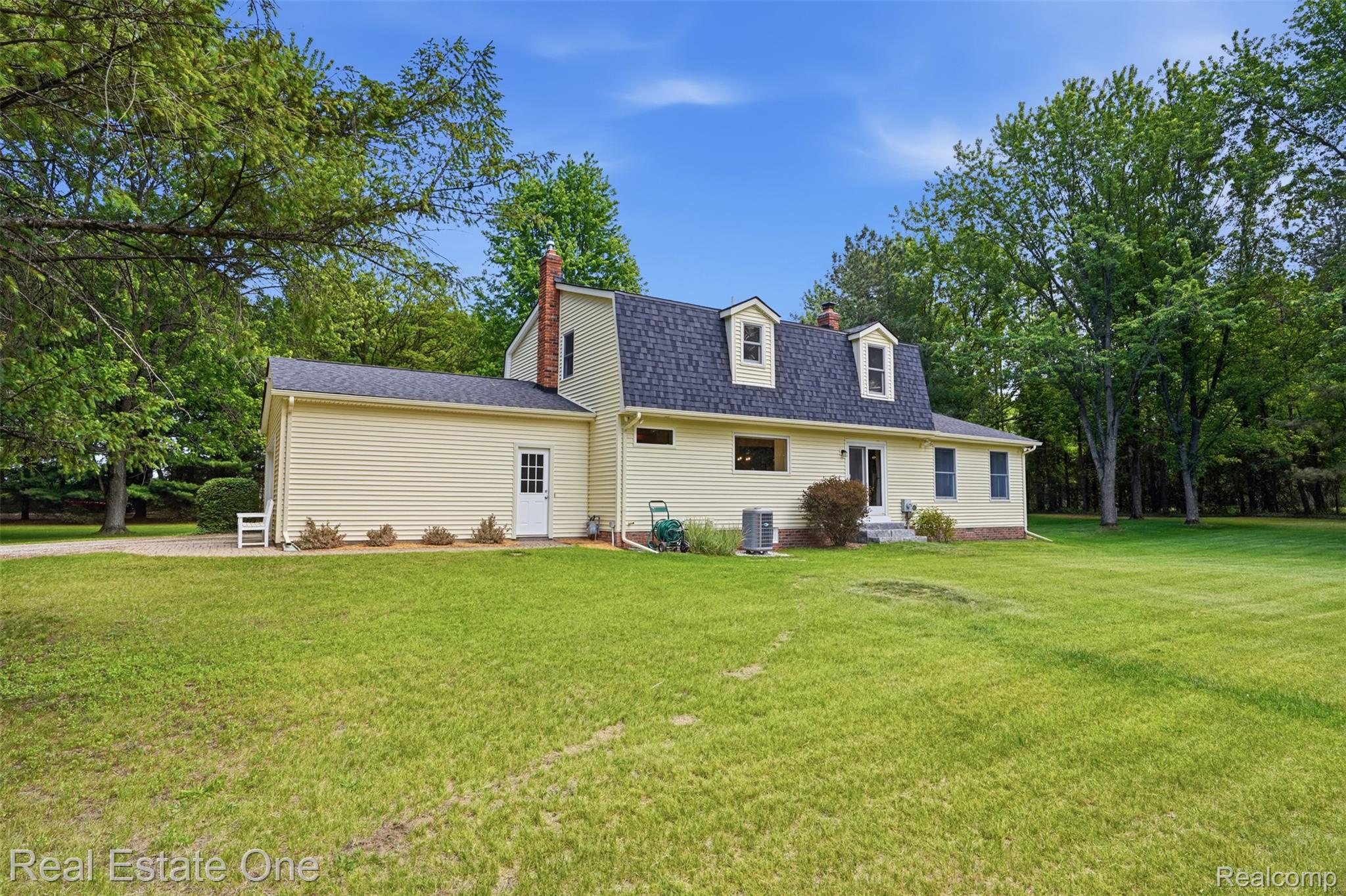 1765 Rowe Road Milford, MI 48380 - Photo 40 of 61 Expansive green lawn surrounds the residence, featuring light yellow siding and a dark shingle roof