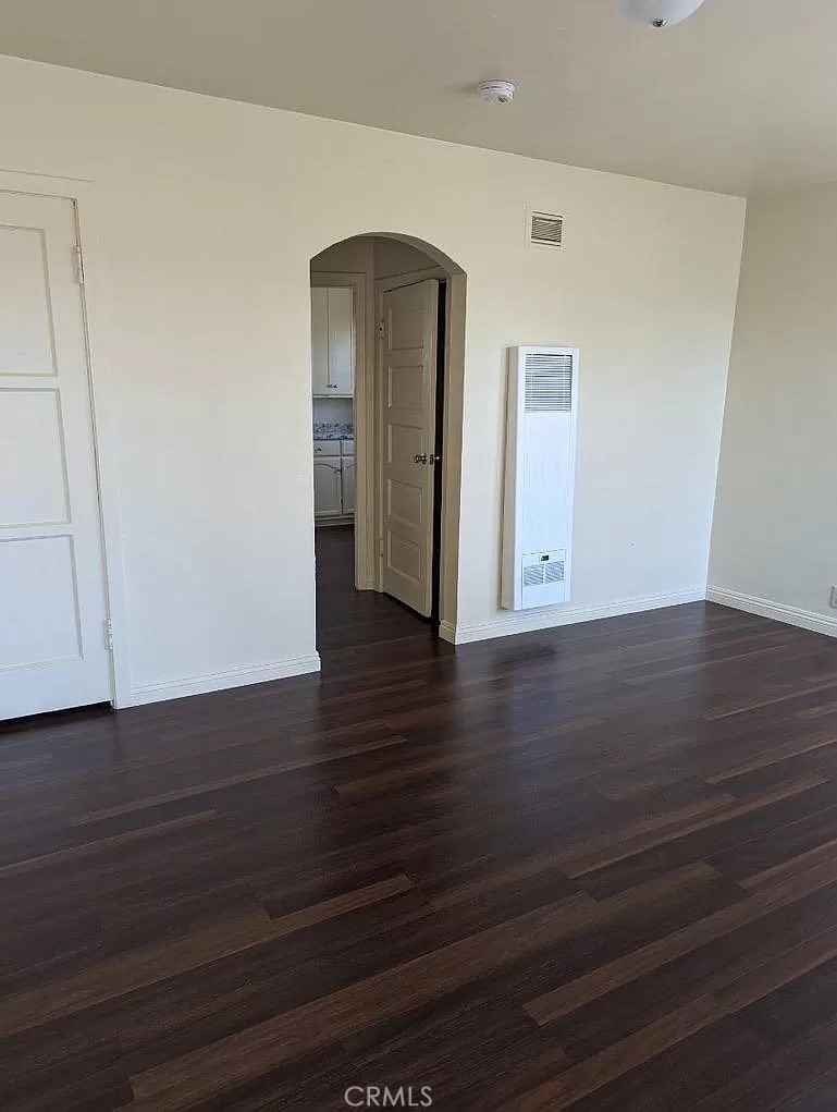 a view of an empty room with wooden floor and closet