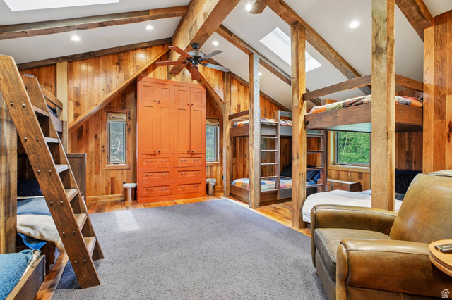10205 East Moose Loop Road Salt Lake City, UT 84121 - Photo 22 of 50 Vaulted ceiling with exposed wood beams, skylights, wood paneling, wood-finish flooring, and a built-in orange cabinetry unit