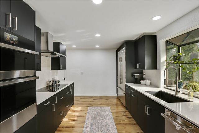 a large kitchen with stainless steel appliances a sink and a stove