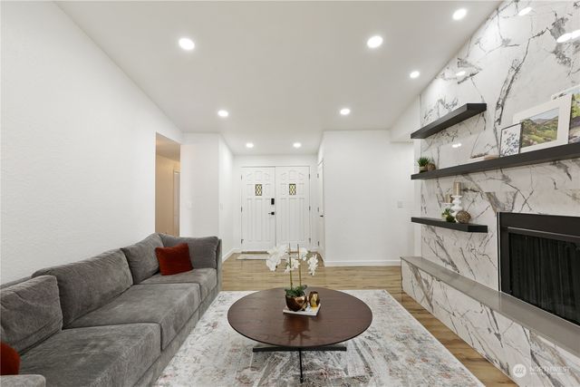 a living room with stainless steel appliances granite countertop a sink a couch a stove a dining table and chairs