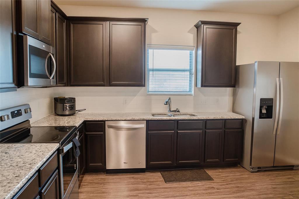 1837 Rialto Lane Crowley, TX 76036 - Photo 14 of 19 Kitchen featuring dark wood cabinetry, granite-finish countertops, and stainless steel appliances