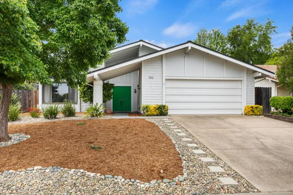 a front view of house with yard and trees in the background