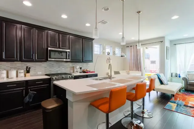 a kitchen with stainless steel appliances granite countertop a sink a stove a refrigerator cabinets and chairs