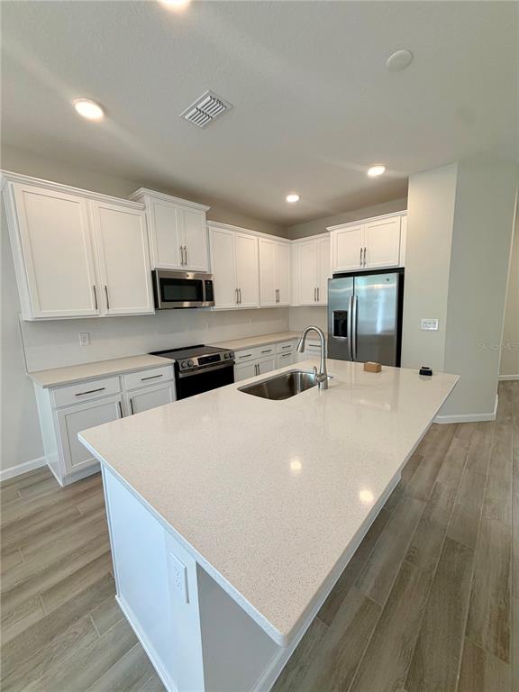 5222 Ctr Lk Rnch Boulevard St. Cloud, FL 34771 - Photo 2 of 25 a large white kitchen with wooden floors stainless steel appliances and white cabinets