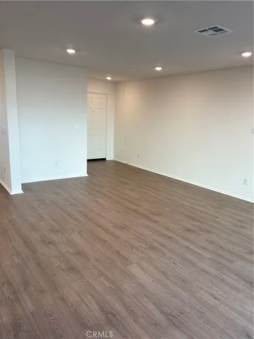 an empty room with wooden floor and natural light