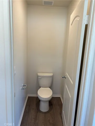 a white toilet sitting in a bathroom next to a wooden floor