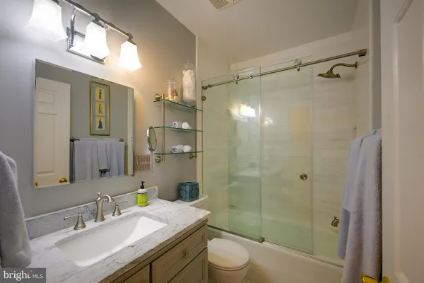 a bathroom with a granite countertop shower sink vanity mirror and toilet