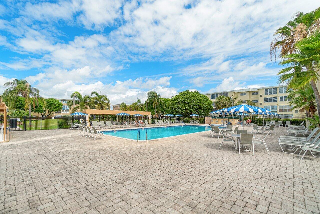 2615 Northeast 3rd Street, Unit 308 Boynton Beach, FL 33435 - Photo 23 of 27 a view of a swimming pool with lawn chairs and a big yard