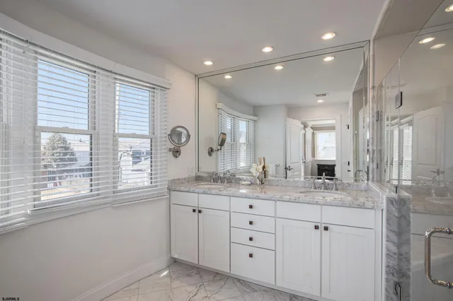 a bathroom with a granite countertop sink mirror and window