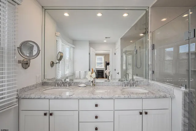 a bathroom with a granite countertop sink a mirror and shower