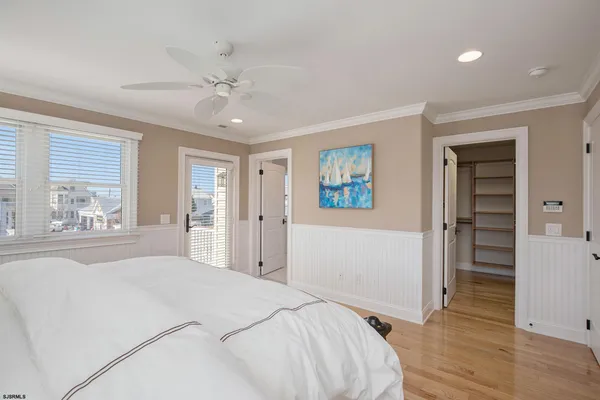 a bedroom with a bed and a large window with wooden floor