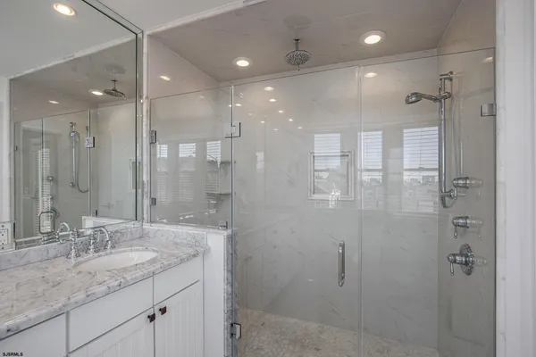a bathroom with a granite countertop sink a shower and a mirror