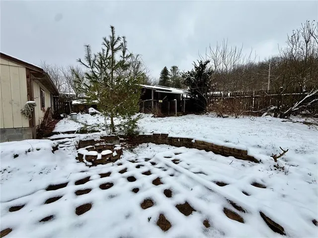 a view of a dry yard covered with snow in front of house