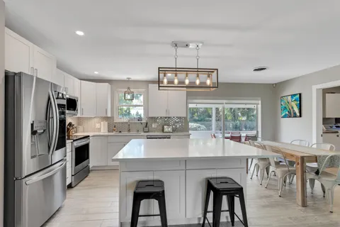 a kitchen with stainless steel appliances a table chairs refrigerator and cabinets