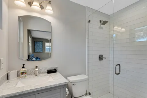 a bathroom with a sink vanity granite toilet and a mirror
