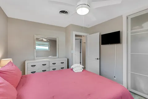a bedroom with a bed and a flat tv screen on dresser