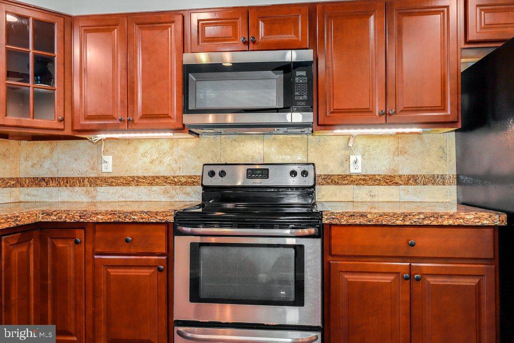 8538 Brest Road Randallstown, MD 21133 - Photo 17 of 47 a kitchen with granite countertop a stove top oven microwave and cabinets