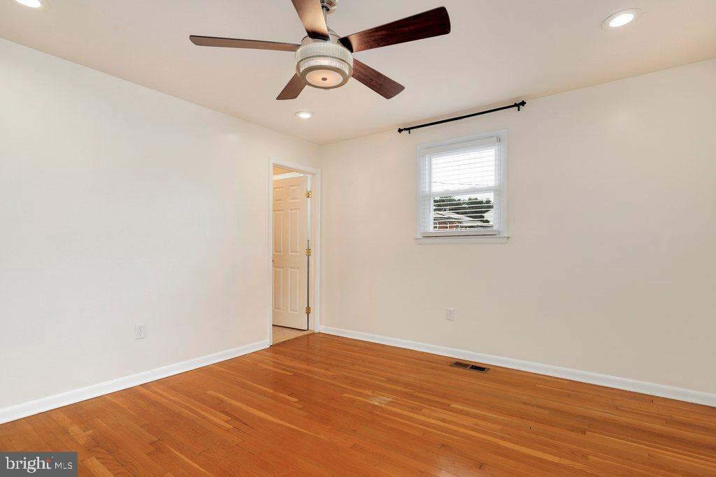 8538 Brest Road Randallstown, MD 21133 - Photo 24 of 47 an empty room with wooden floor ceiling fan and windows
