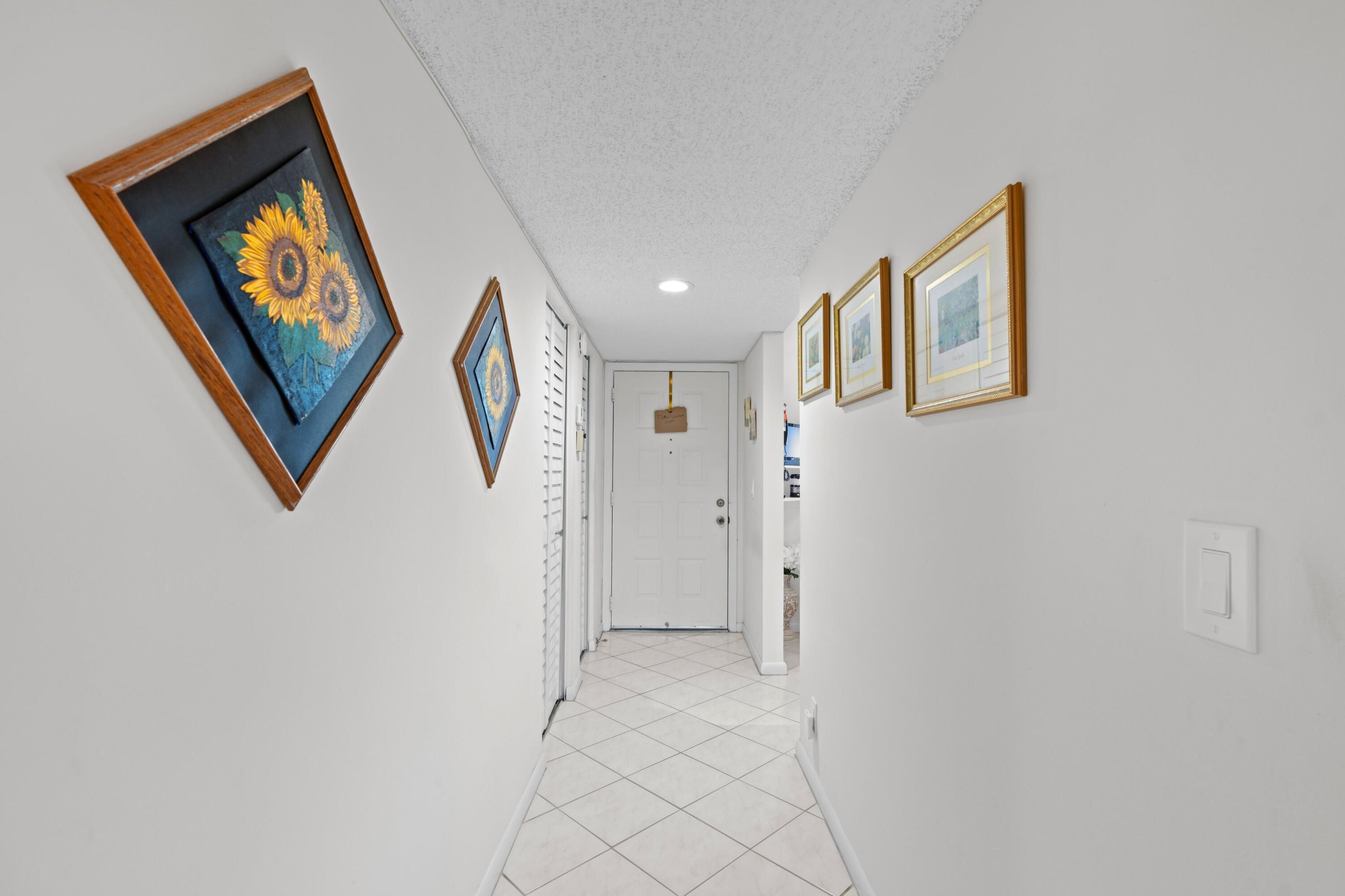 14360 Strathmore Lane, Unit 404 Delray Beach, FL 33446 - Photo 18 of 42 a view of a hallway with paintings on the wall