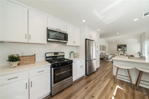 a kitchen with stainless steel appliances white cabinets and wooden floor
