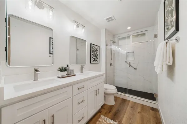 a bathroom with a double vanity sink toilet mirror and shower