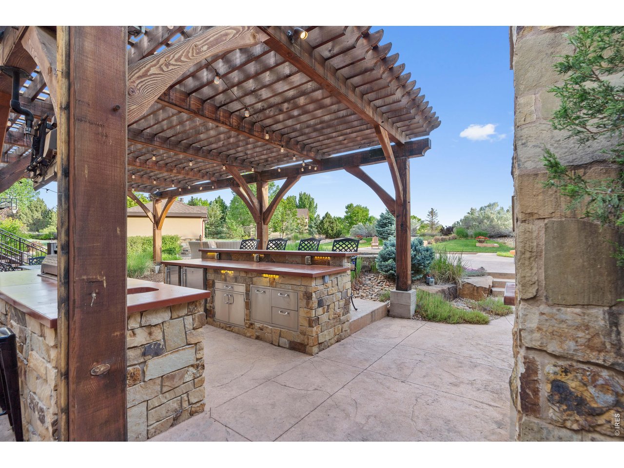 964 Riparian Way Fort Collins, CO 80524 - Photo 17 of 42 a view of a patio with table and chairs under an umbrella with a large tree