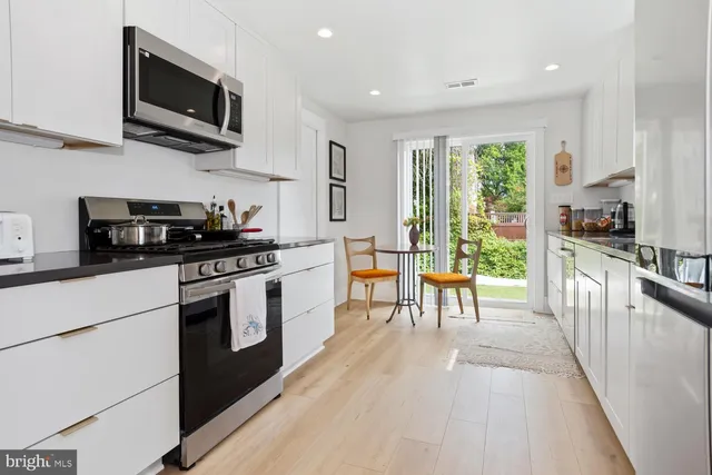 a kitchen with stainless steel appliances kitchen island granite countertop a stove a sink and a microwave
