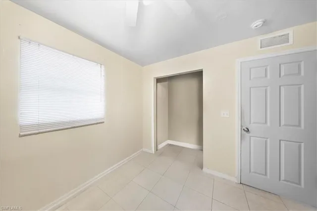 an empty room with windows and fan