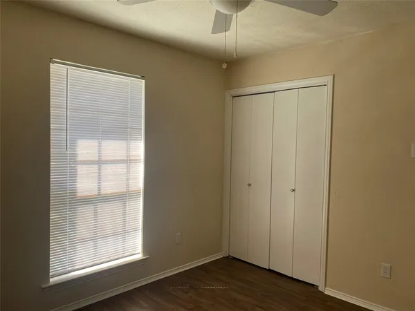 an empty room with wooden floor cabinet and windows