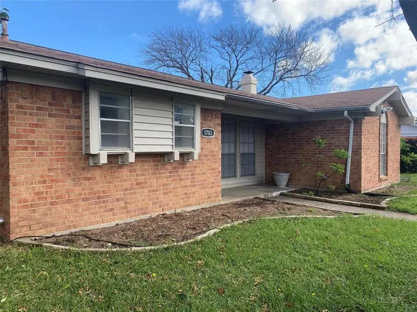 a brick house with a yard and large tree