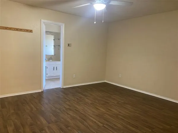a view of an empty room with wooden floor and a chandelier