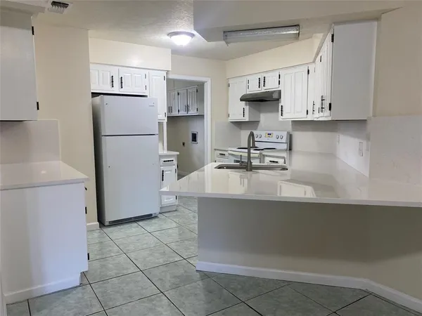 a kitchen with a sink a refrigerator and a stove top oven