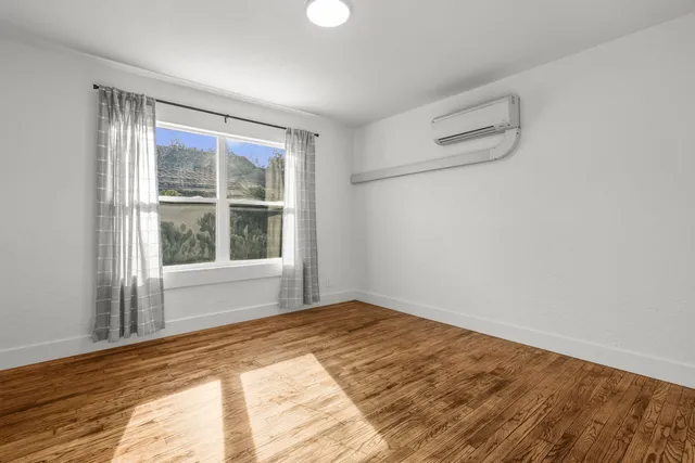 a view of an empty room with wooden floor and a window