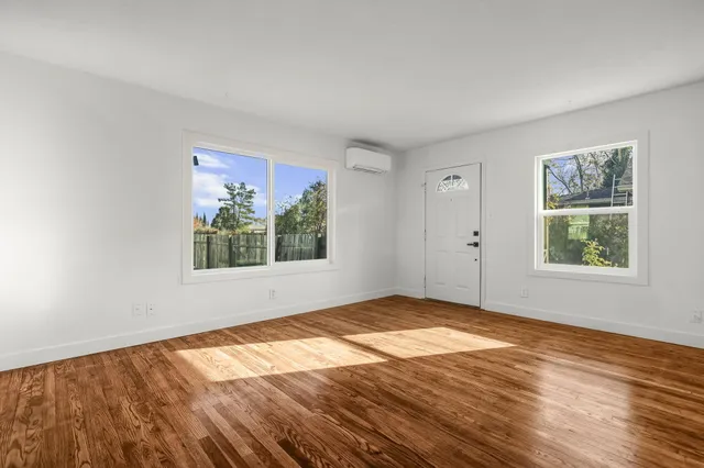 a view of an empty room with window and wooden floor