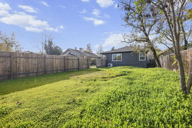 a view of a house with a big yard and large tree