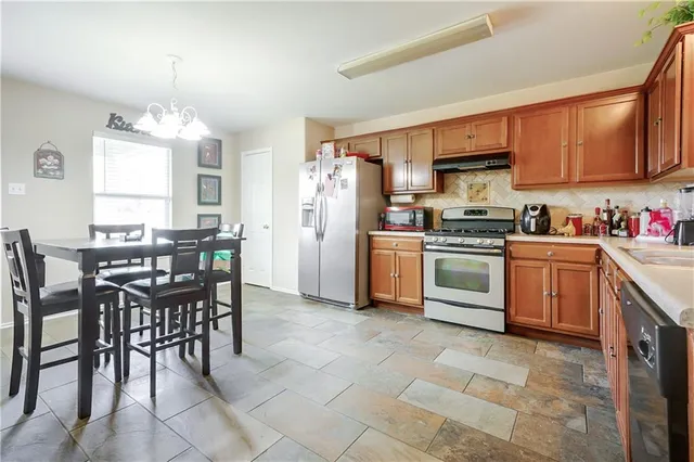 a kitchen with stainless steel appliances a table chairs sink refrigerator and cabinets